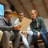 Drei Menschen vom Jugendmigrationsdienst lesen gemeinsam