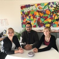 Drei Menschen vom Jugendmigrationsdienst sitzen am Tisch